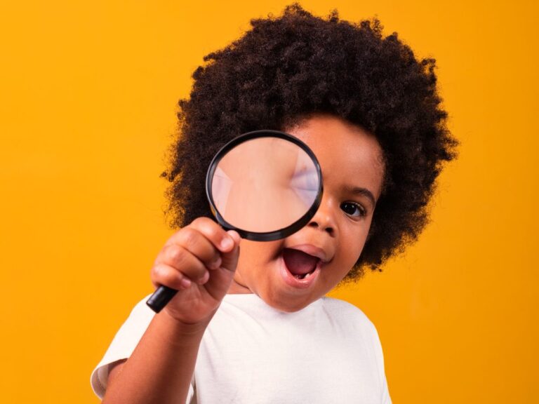 A curious little boy peers through a magnifying glass